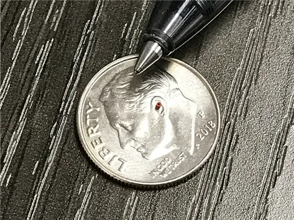 Laser-machined silicone gasket (0.64mm OD – 0.125mm ID) compared size comparison with US dime and ball point pen.