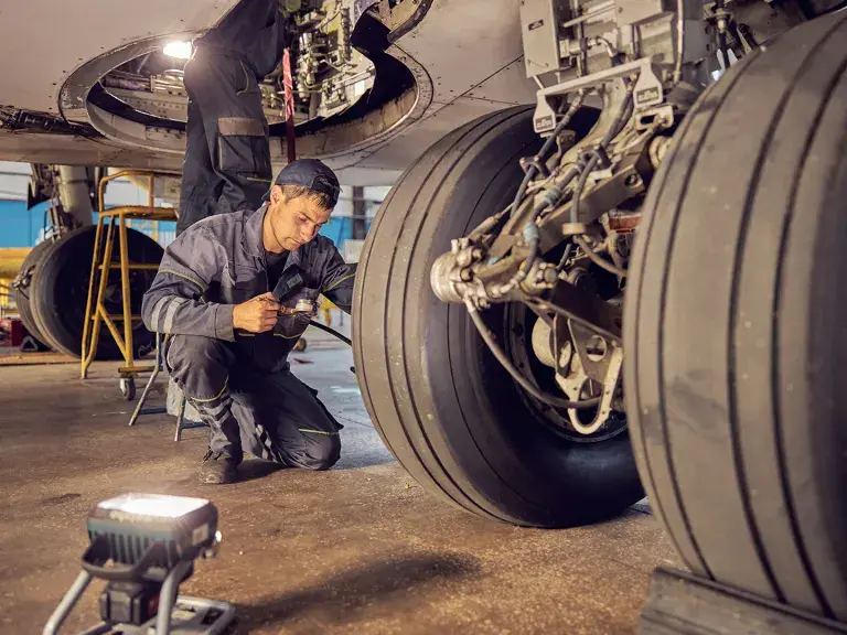 Landing gear airplane in hangar chassis rubber with aviation worker in uniform