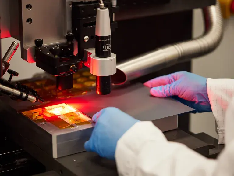 Lab coat and lab gloves place metal into laser machine